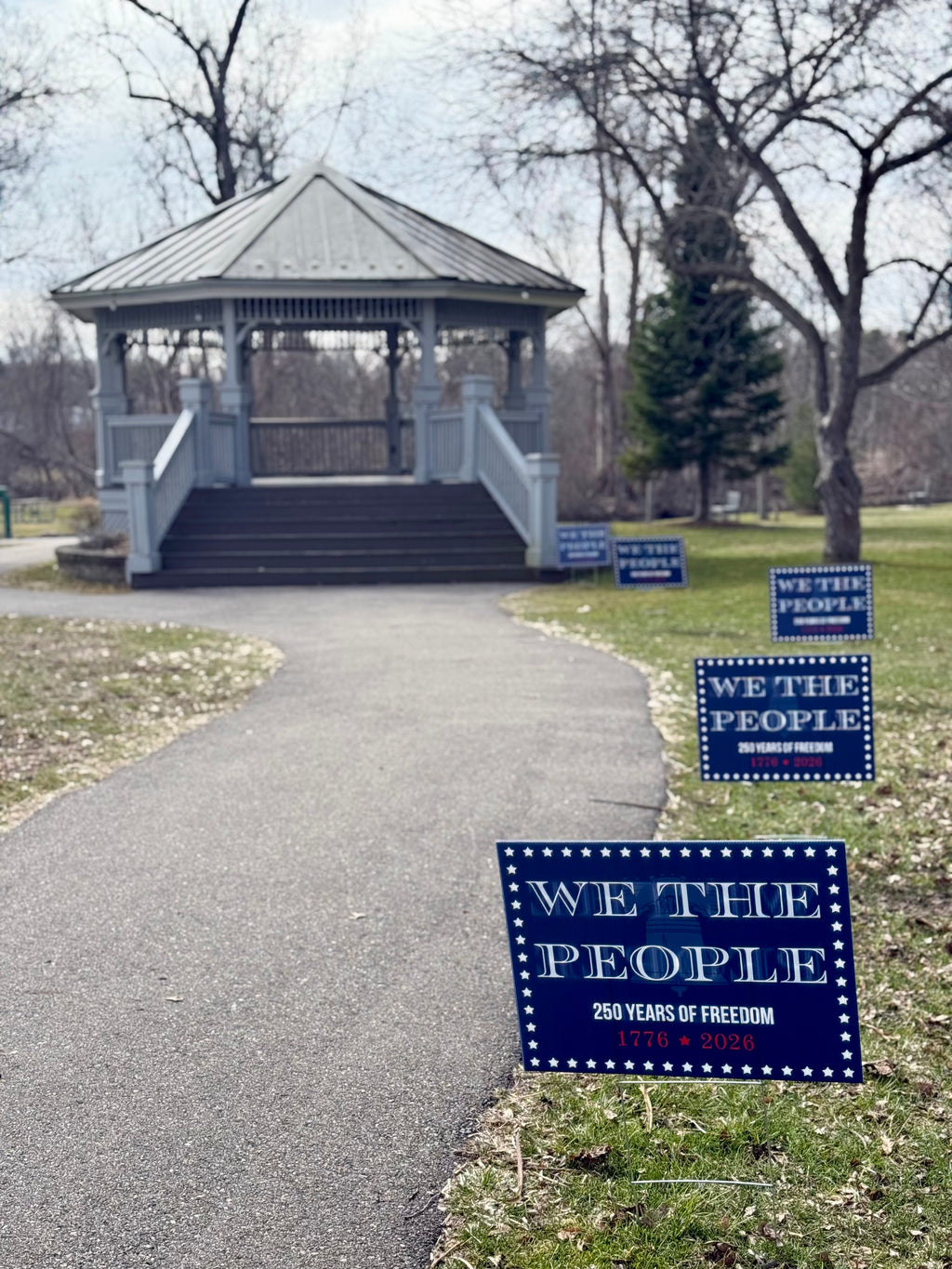 We the People' America 250 yard sign  in a park setting
