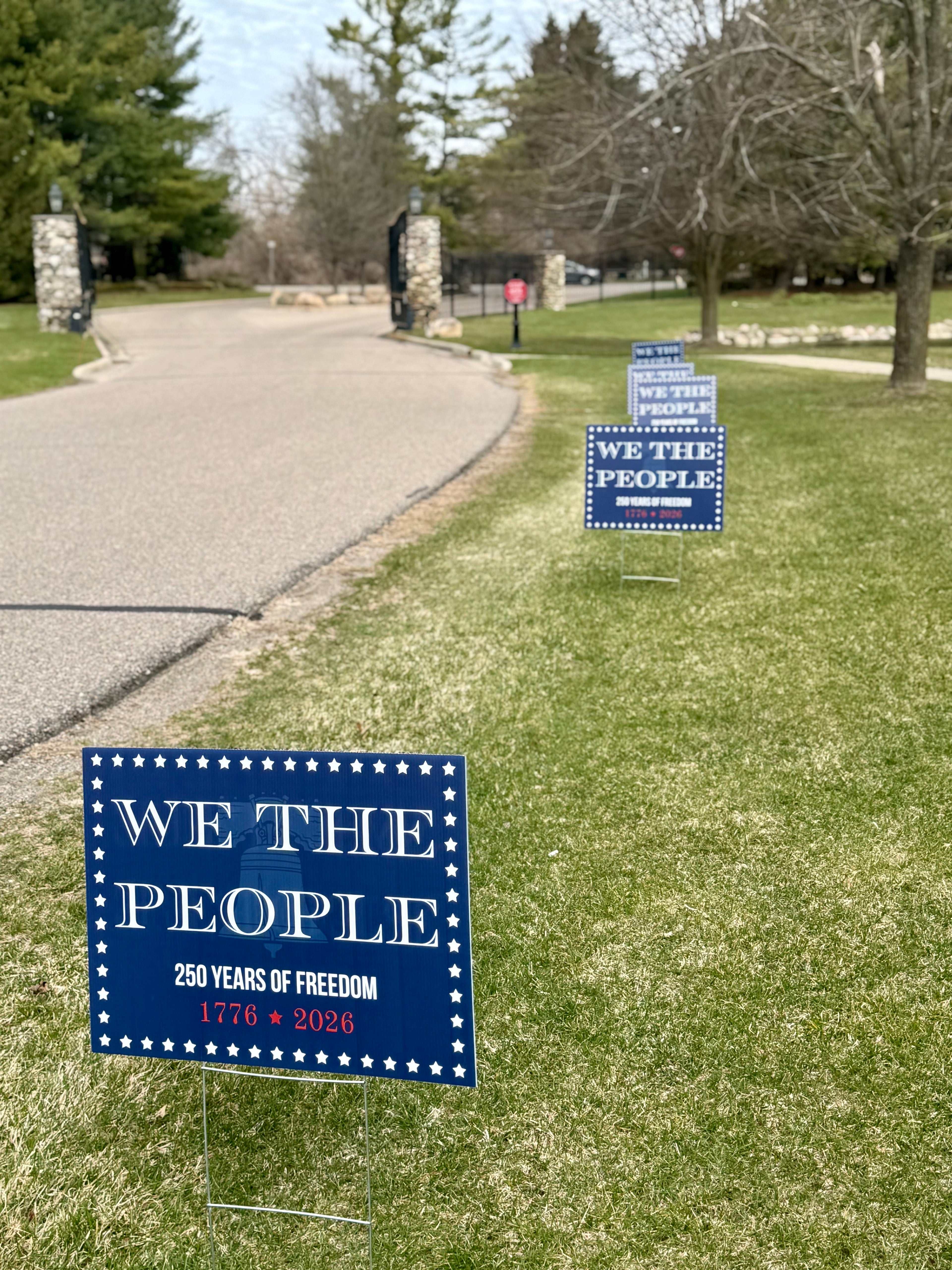 America 250 Row of bulk 'We the People' signs on a grassy lawn subdivision entrance